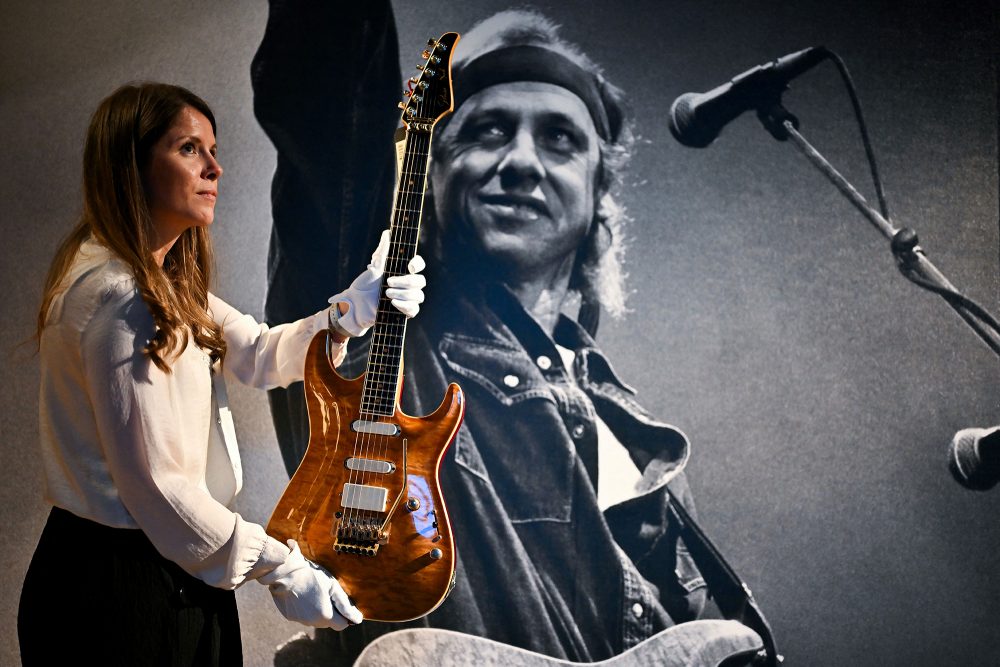 Eine Mitarbeiterin vom Auktionshaus Christie's mit einer der zu versteigernden Gitarren von Mark Knopfler (Bild: Ben Stansall/AFP)