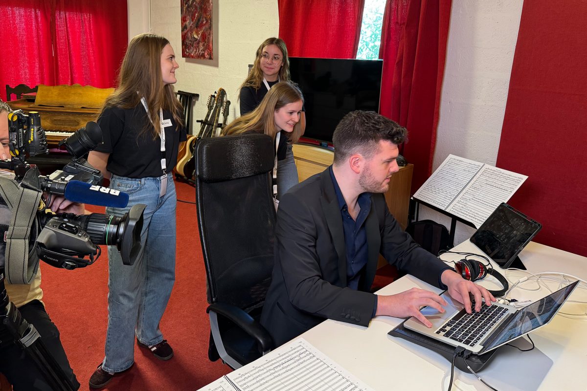 Filmkomponist Vitaly Jardon bei der Arbeit - die Journalisten für einen Tag, Angelina, Salome und Elena schauen ihm über die Schulter (Bild: Robin Emonts/BRF)