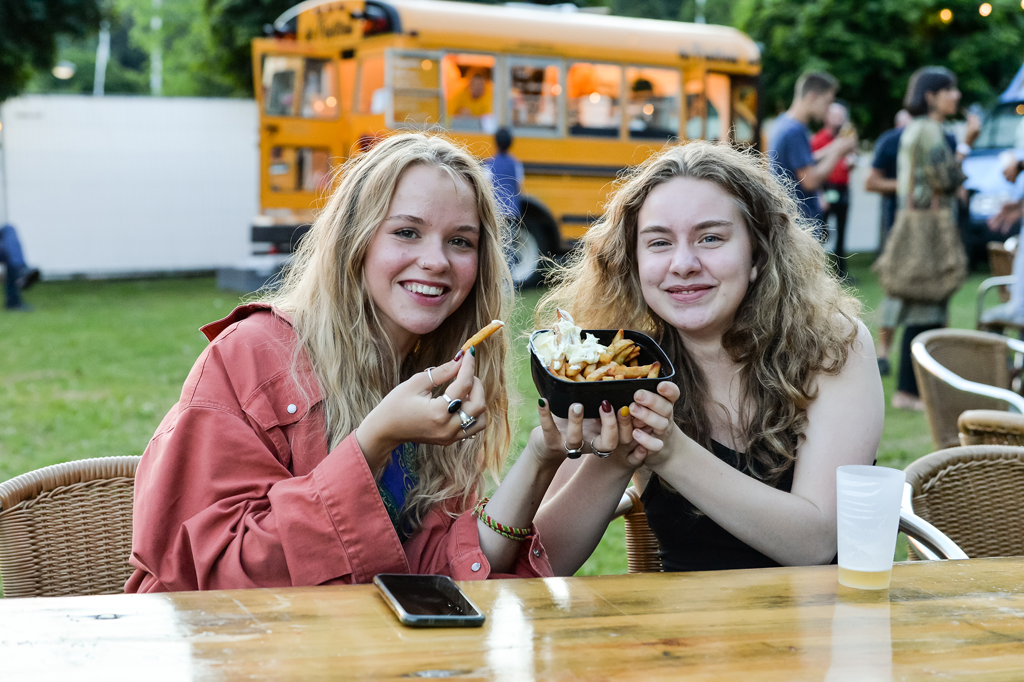 Zwei Festivalbesucherinnen in Genk mit wiederverwendbarer Frittenschale und Mehrwegbecher (Bild: Jill Delsaux/Belga)