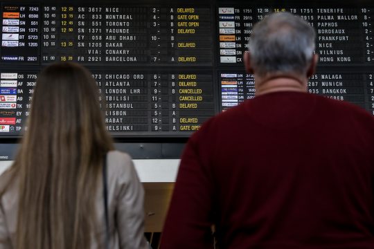 Reisende schauen auf die Abflugtafel am Brussels Airport