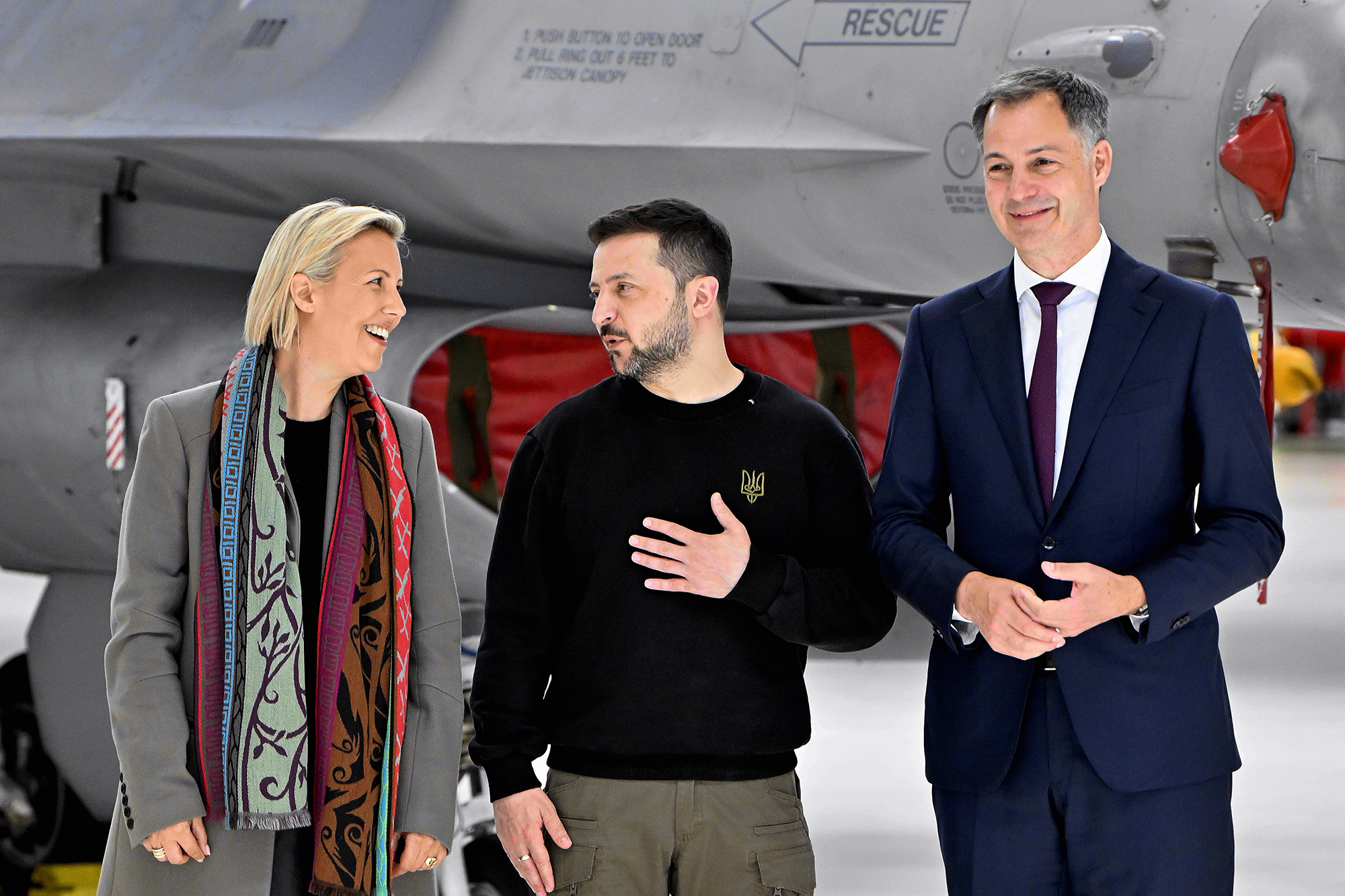 Verteidigungsministerin Ludivine Dedonder, der ukrainische Präsident Wolodymyr Selenskyj und Premierminister Alexander De Croo am Dienstag vor einem F-16-Kampfflugzeug am Militärflughafen Melsbroek