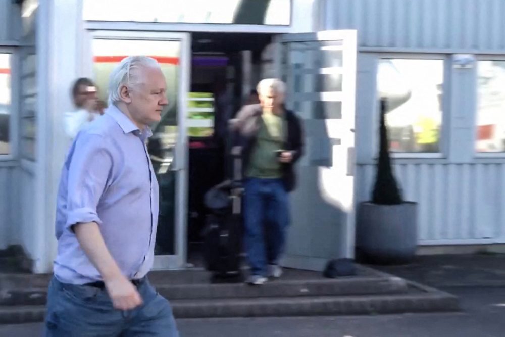 Julian Assange auf dem Weg in ein Flugzeug am Londoner Flughafen Stansted