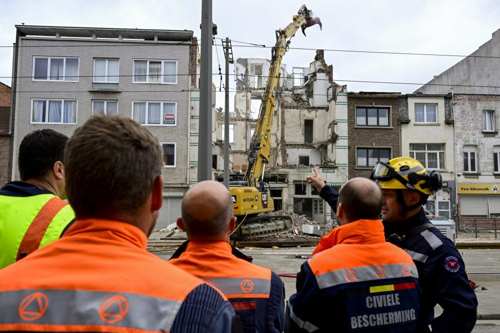 Einsatzkräfte stehen vor dem eingestürzten Appartementgebäude in Antwerpen