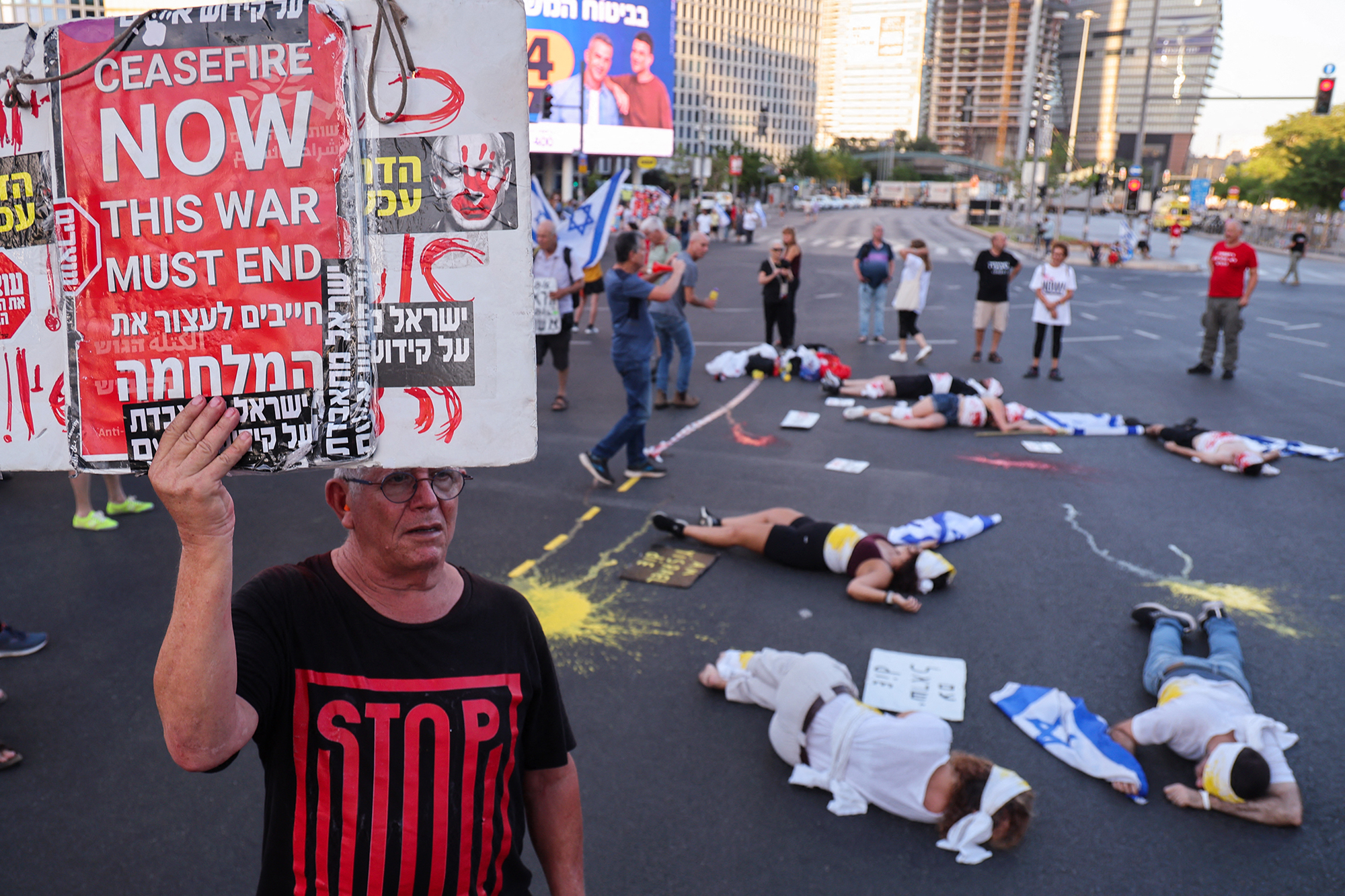 Linke Aktivisten halten Plakate und Nationalflaggen während einer regierungskritischen Demonstration in der israelischen Küstenstadt Tel Aviv in die Höhe