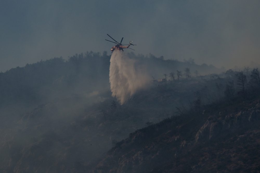 Ein Hubschrauber versprüht Wasser über einem Waldbrand auf dem Berg Parnitha bei Athen