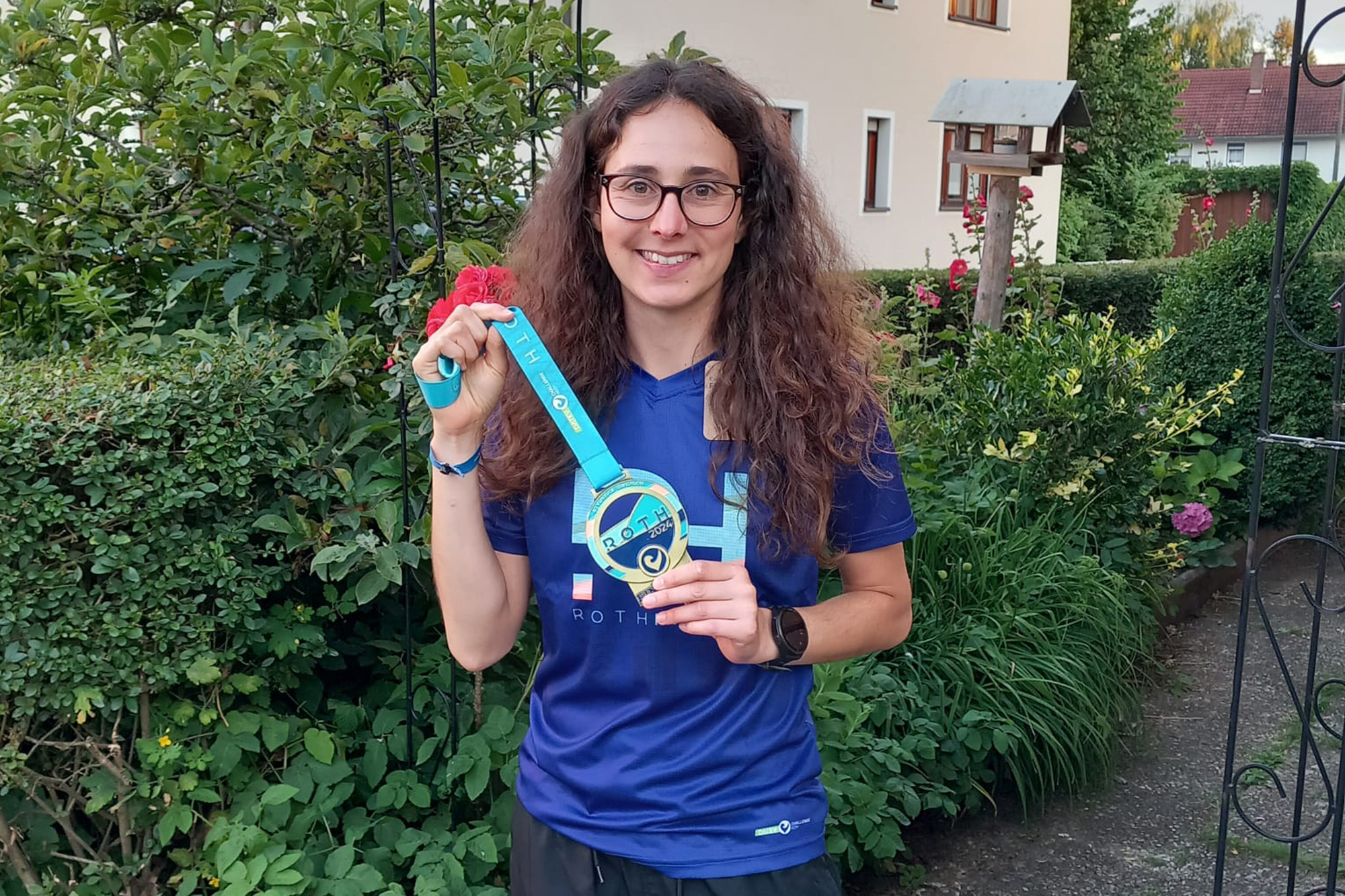 Jana Backes hält ihre Medaille vom Triathlon in Roth in den Händen