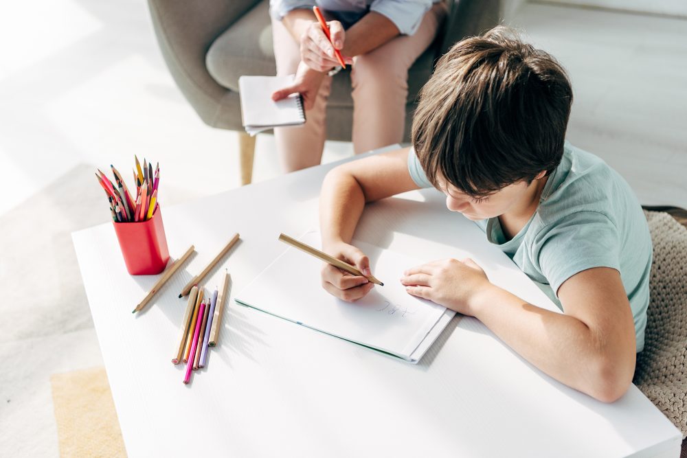 Kind beim Malen unter Aufsicht einer Psychologin