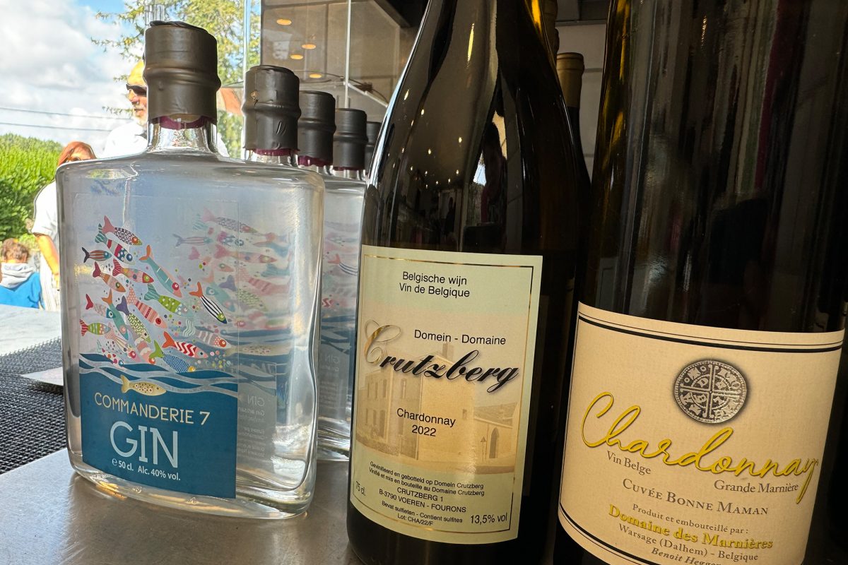 Eine Flasche Gin der Commanderie N°7 neben zwei Weinflaschen mit Chardonnay von belgischen Weingütern