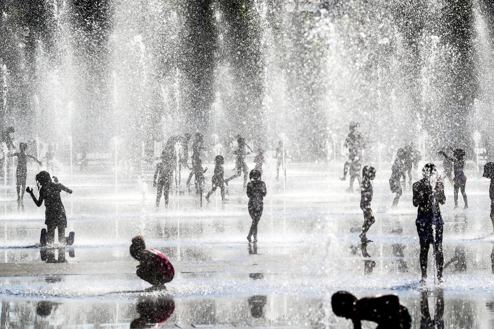 Kinder spielen während einer Hitzewelle in der französischen Riviera-Stadt Nizza unter Wasserdüsen und kühlen sich in Springbrunnen ab