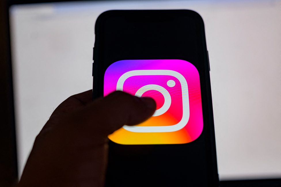 Hand hält Smartphone, auf dessen Display das Instagram-Logo angezeigt wird
