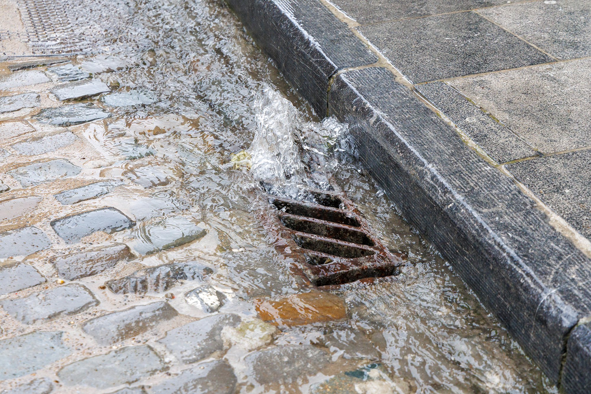 Eine große Menge Regenwasser läuft in einer Brüsseler Straße in einen Gully