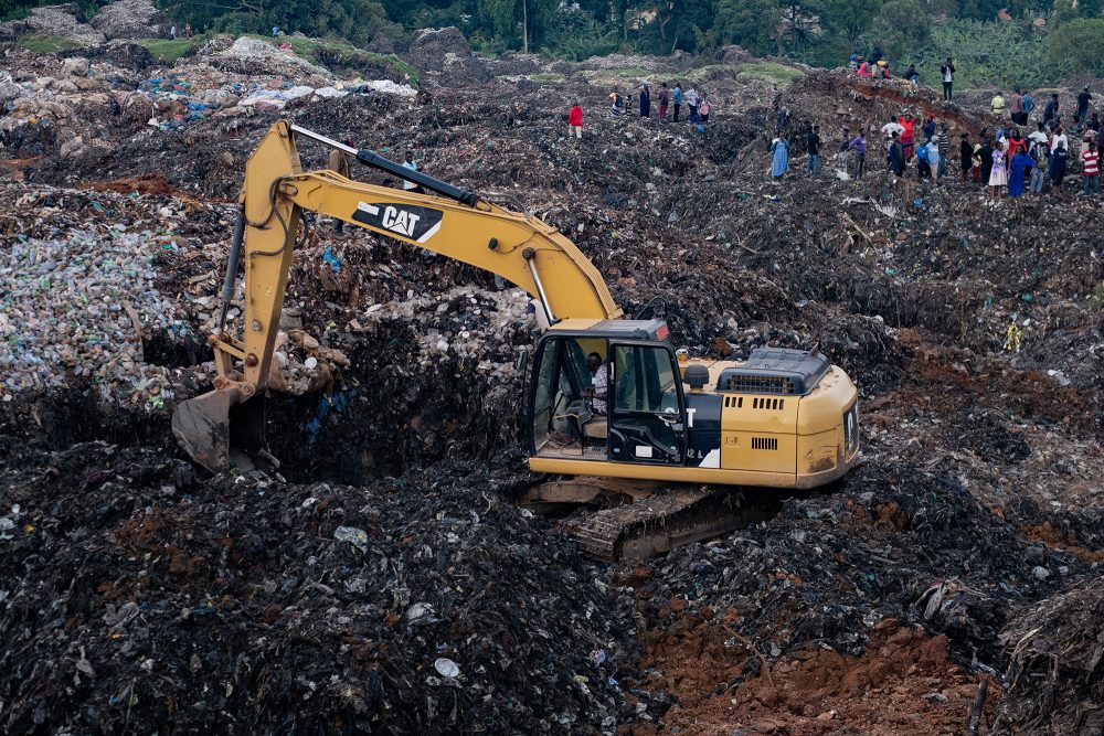 Ein Bagger hilft bei der Suche nach Menschen, die nach dem Einsturz einer Mülldeponie in der ugandischen Hauptstadt Kampala unter den Trümmern gefangen sind