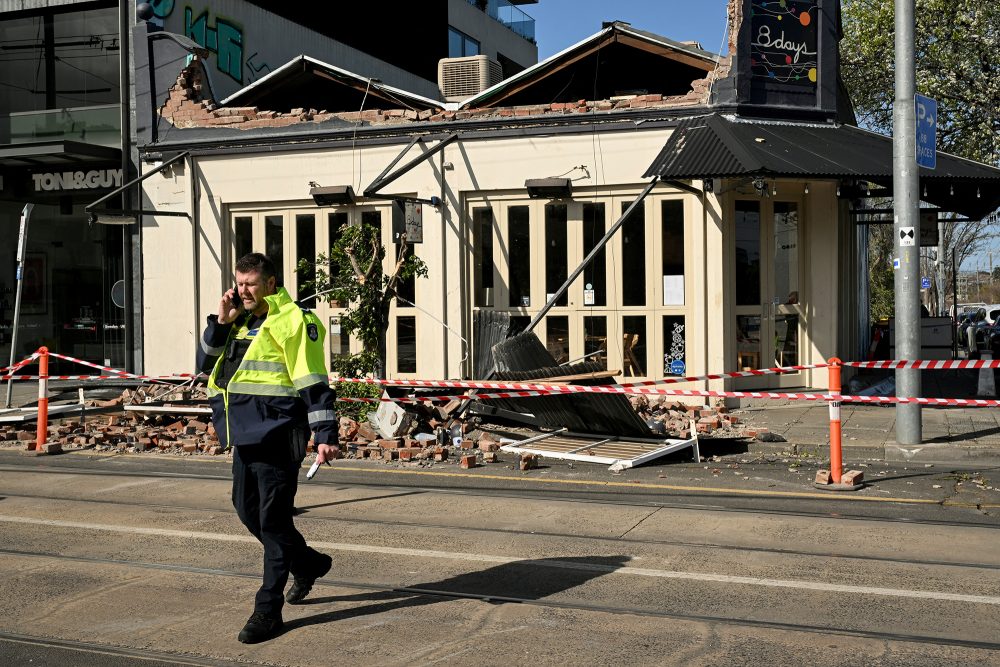 Ein Polizist geht an einer eingestürzten Gebäudefassade in Melbourne vorbei, während Wind mit Geschwindigkeiten von mehr als 110 Kilometern pro Stunde über die Region hinwegfegt