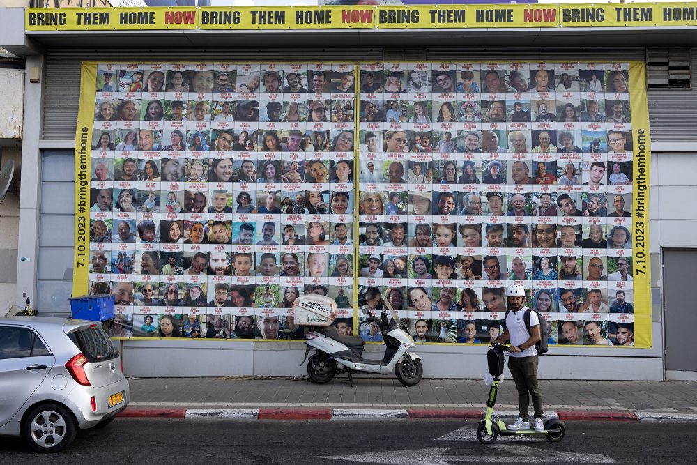 Ein Mann fährt in Tel Aviv auf einem Roller an Plakaten von Israelis vorbei, die seit den Anschlägen vom 7. Oktober von militanten Palästinensern im Gazastreifen als Geiseln festgehalten werden