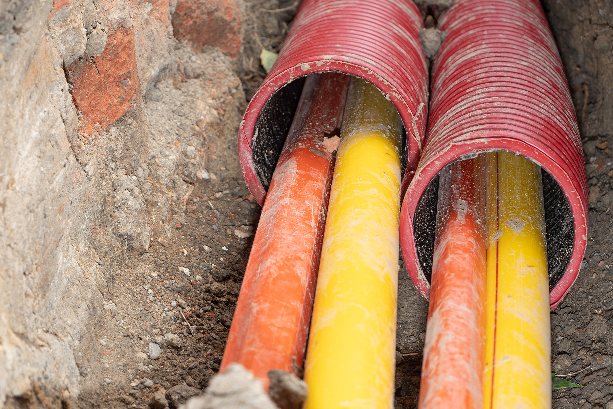 Das Foto zeigt Glasfaserleitungen, die unter der Erde verlegt werden, und dient als Illustrationsbild für die Eifel-Pipeline