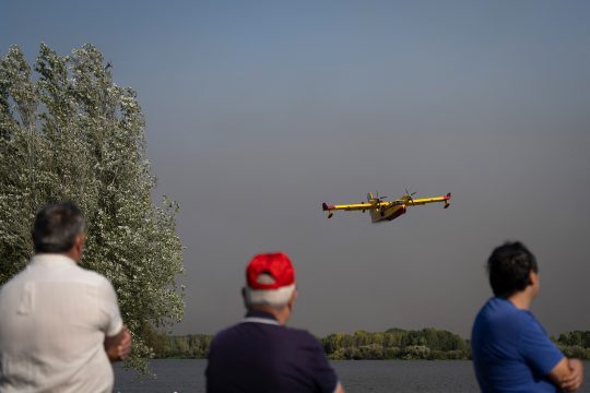 Menschen beobachten ein spanisches Löschflugzeug während eines Waldbrands in der portugiesischen Stadt Aveiro