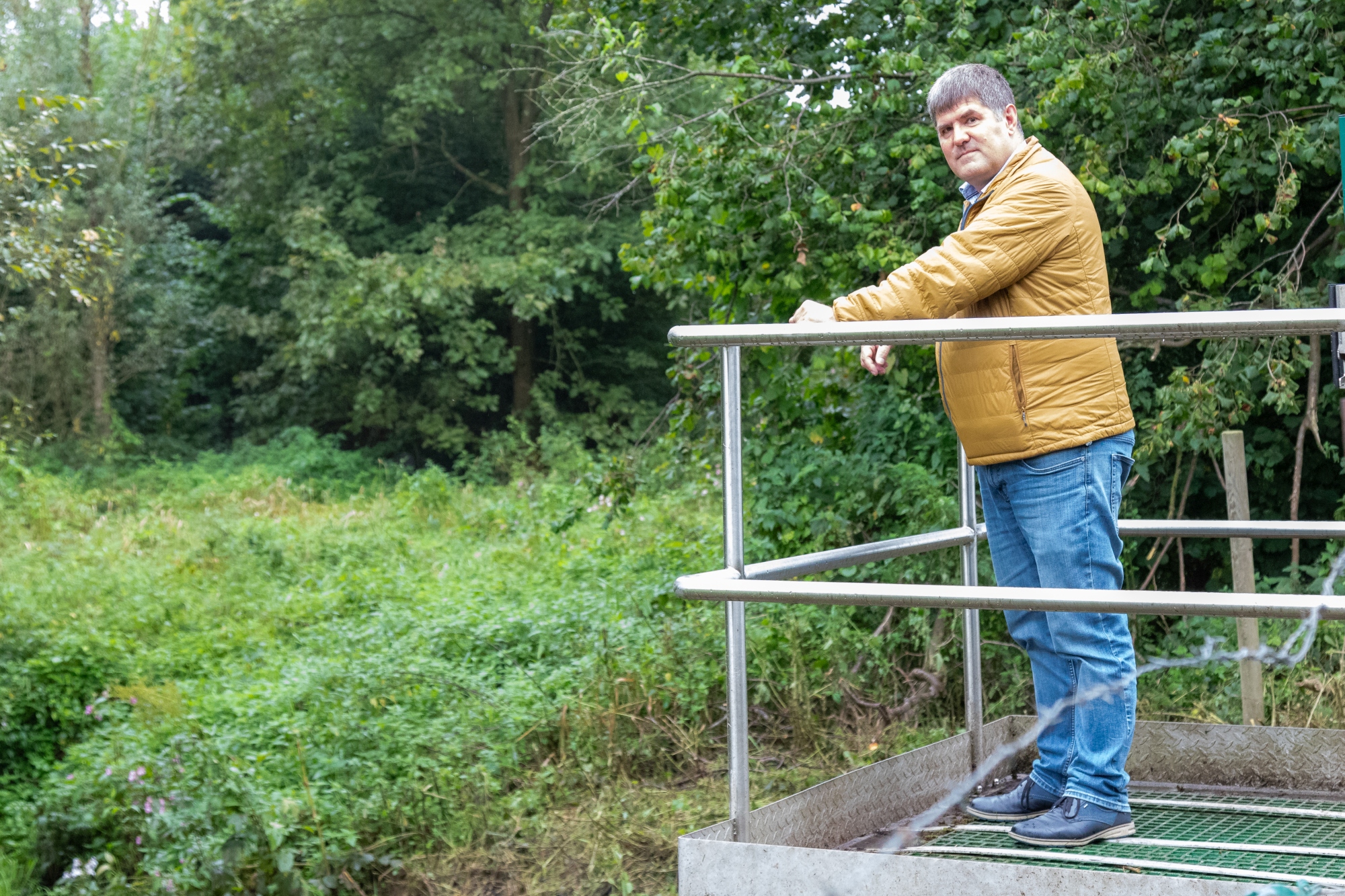 Raerens Bürgermeister Mario Pitz auf dem Regulierungsschacht eines Regenrückhaltebeckens in Raeren (Bild: Olivier Krickel/BRF)