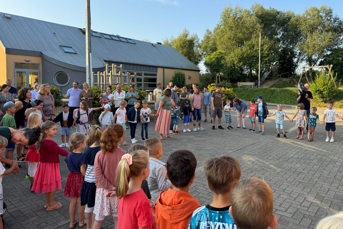 Schüler, Eltern und Lehrer bilden einen Kreis auf dem Schulhof der Grundschule Walhorn