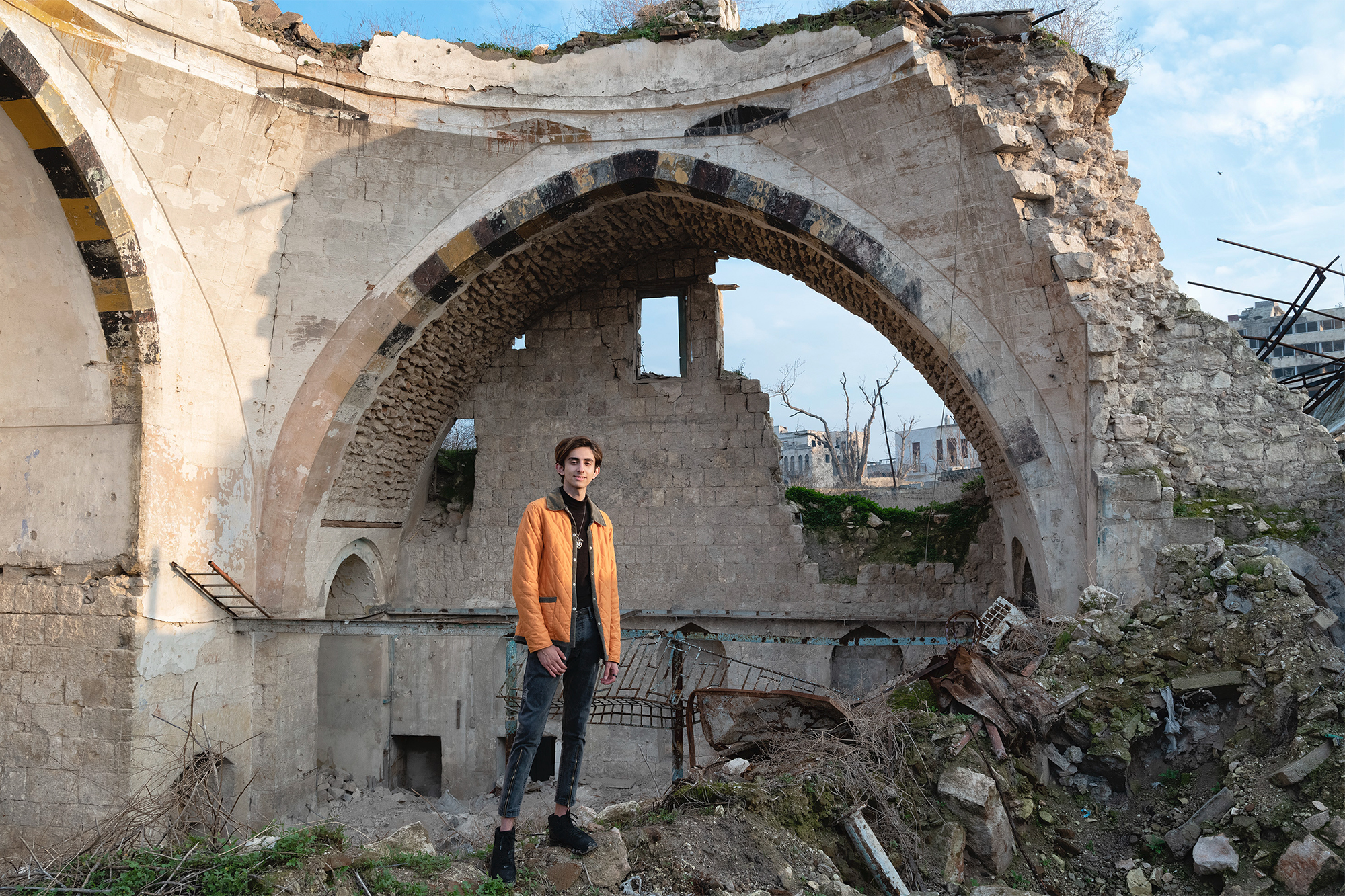 Der 18-jährige Sam Houri inmitten eines zerstörten Gebäudes - Fotografie aus dem Werk "Lernen, leben, träumen. Jugend in Aleppo 2020" von Willi Filz