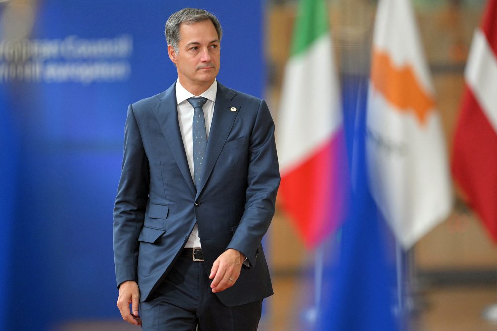 Premierminister Alexander De Croo auf dem Weg zum EU-Gipfeltreffen in Brüssel, im Hintergrund sind verschwommen mehrere Landesflaggen zu sehen