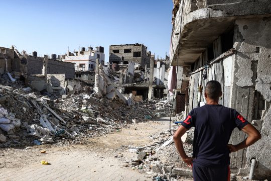 Ein Mann ist von hinten zu sehen, wie er auf mehrere zerstörte Häuser in Bureij im Gazastreifen blickt