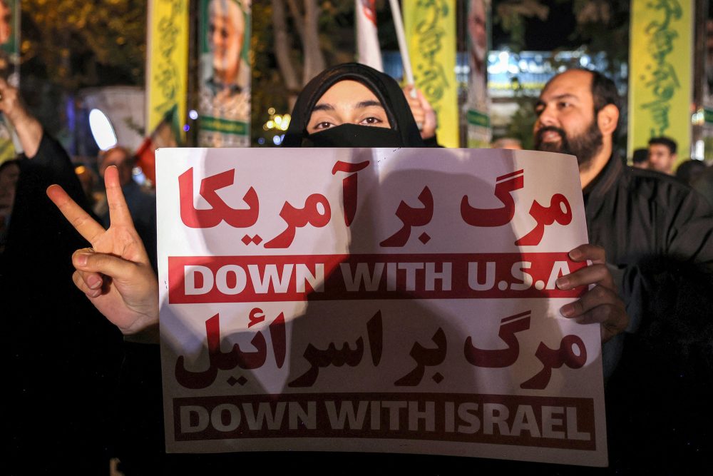 Eine Frau hält auf einer Kundgebung in Teheran ein Schild in die Luft mit der Aufschrift "Nieder mit den USA" und "Nieder mit Israel"