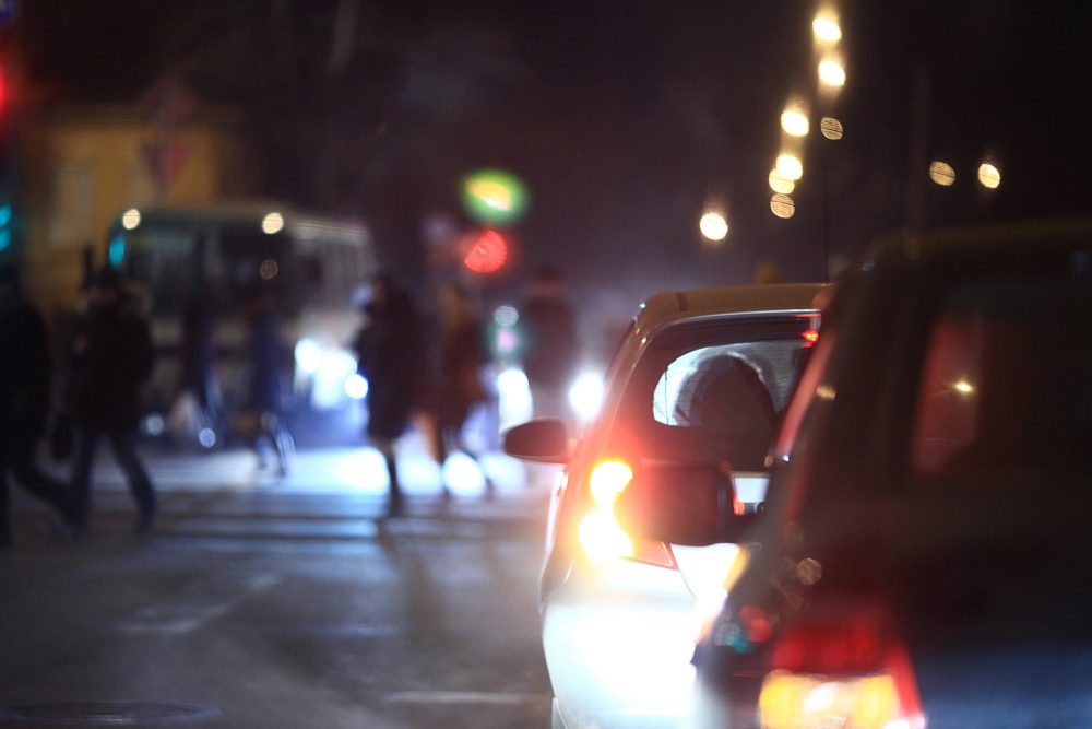 Autos und Fußgänger bei Dunkelheit