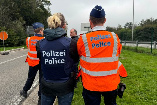 Polizeibeamte sind von hinten zu sehen auf einem Rastplatz an der E40