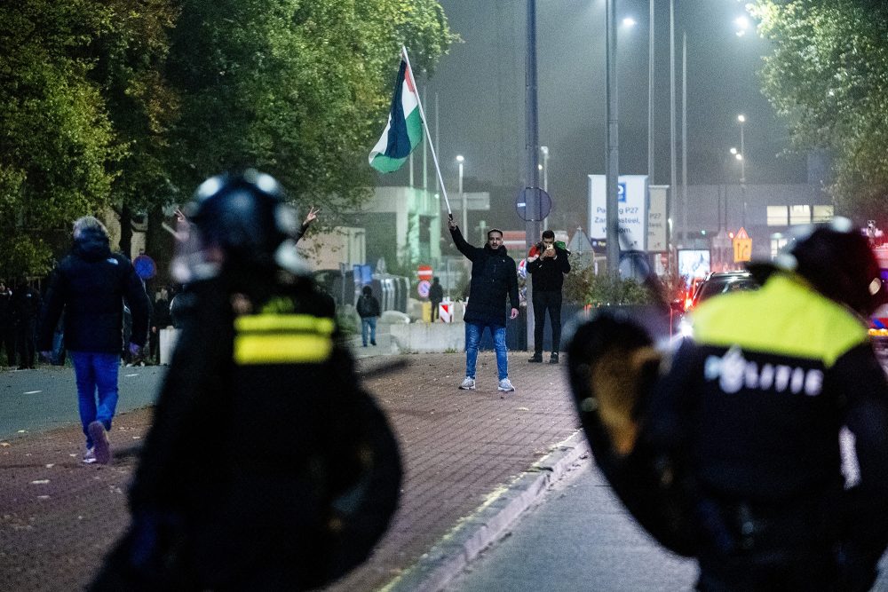 Amsterdam am Donnerstagabend: Mann schwenkt die palästinensische Flagge, Polizisten beobachten die Szene