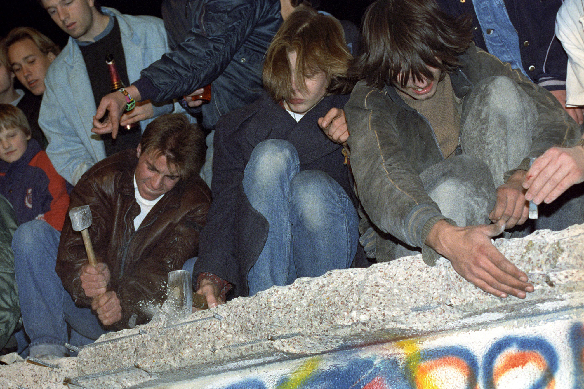 Menschen erklimmen im November 1989 die Berliner Mauer, einige schlagen mit Hammern auf sie ein