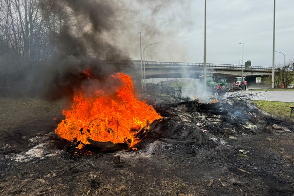 Bauern haben ein Feuer neben der gesperrten Autobahn entzündet