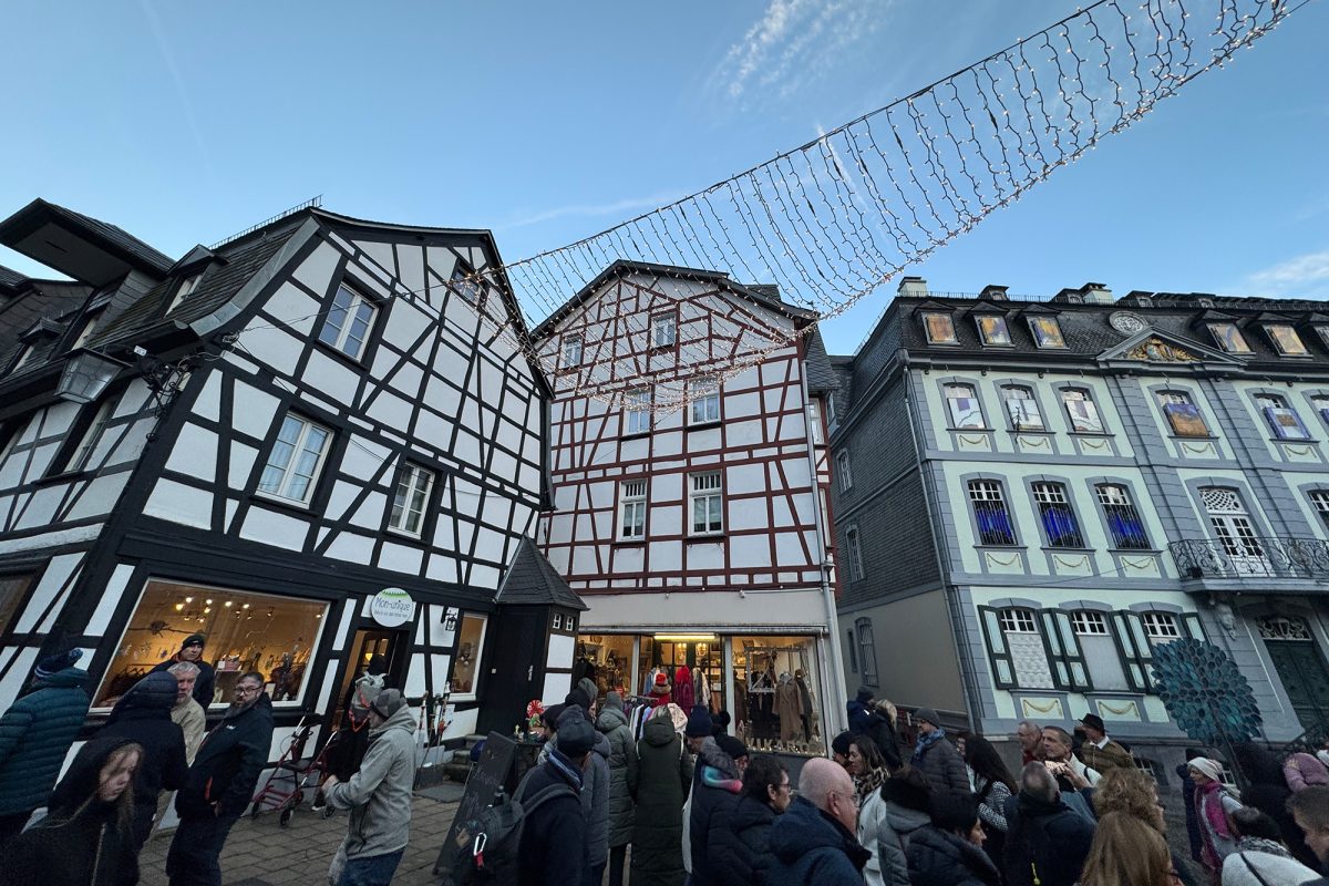 Menschen auf dem Monschauer Weihnachtsmarkt, im Hintergrund historische Fachwerkhäuser