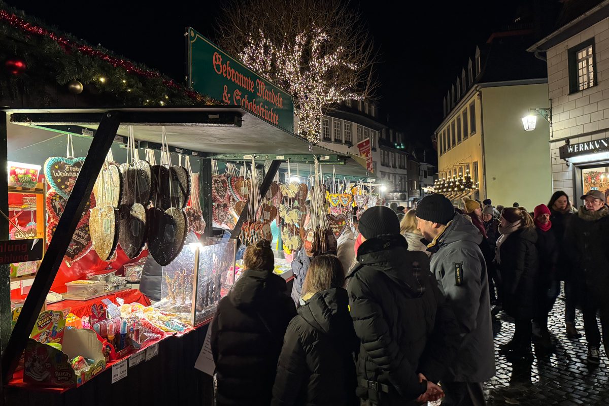 Menschen drängen sich um einen Zuckerwaren-Stand auf dem Monschauer Weihnachtsmarkt