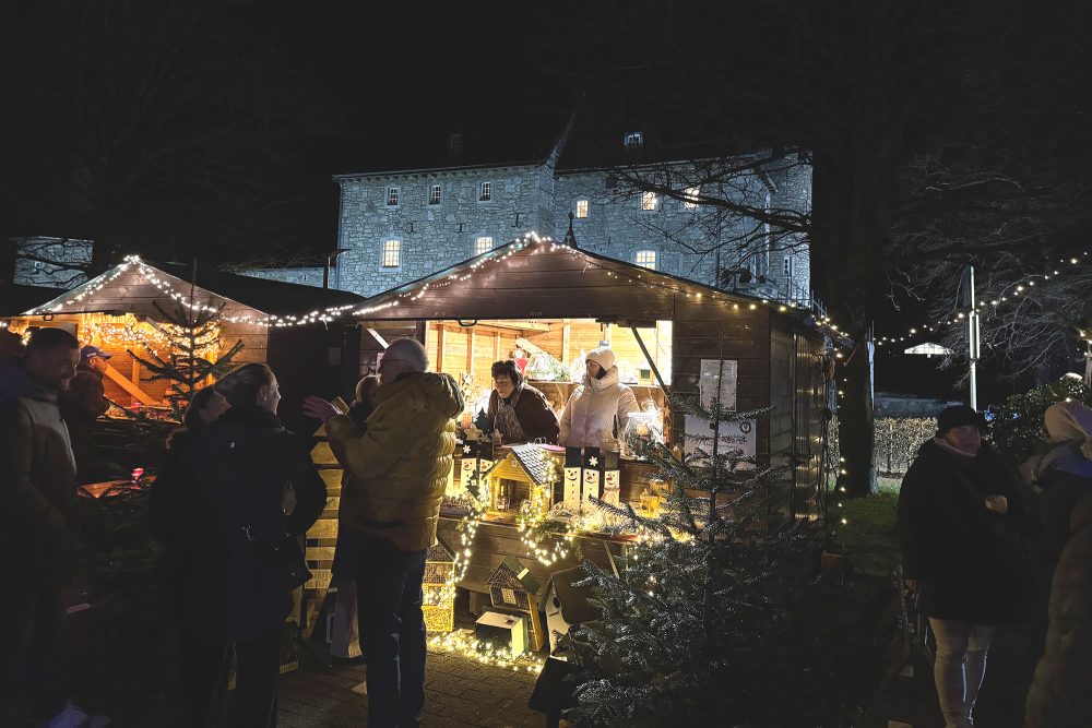 Bude auf dem Raerener Weihnachtsmarkt mit Besuchern im Vordergrund