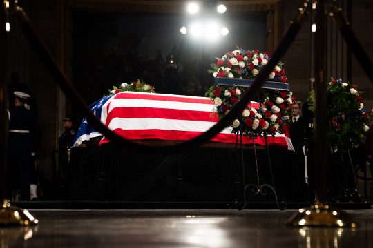 Aufgebahrter Sarg von Ex-US-Präsident Jimmy Carter im Kapitol, auf dem Sarg liegt eine große US-Flagge, ein Trauerblumenbesteck ist davor zu sehen