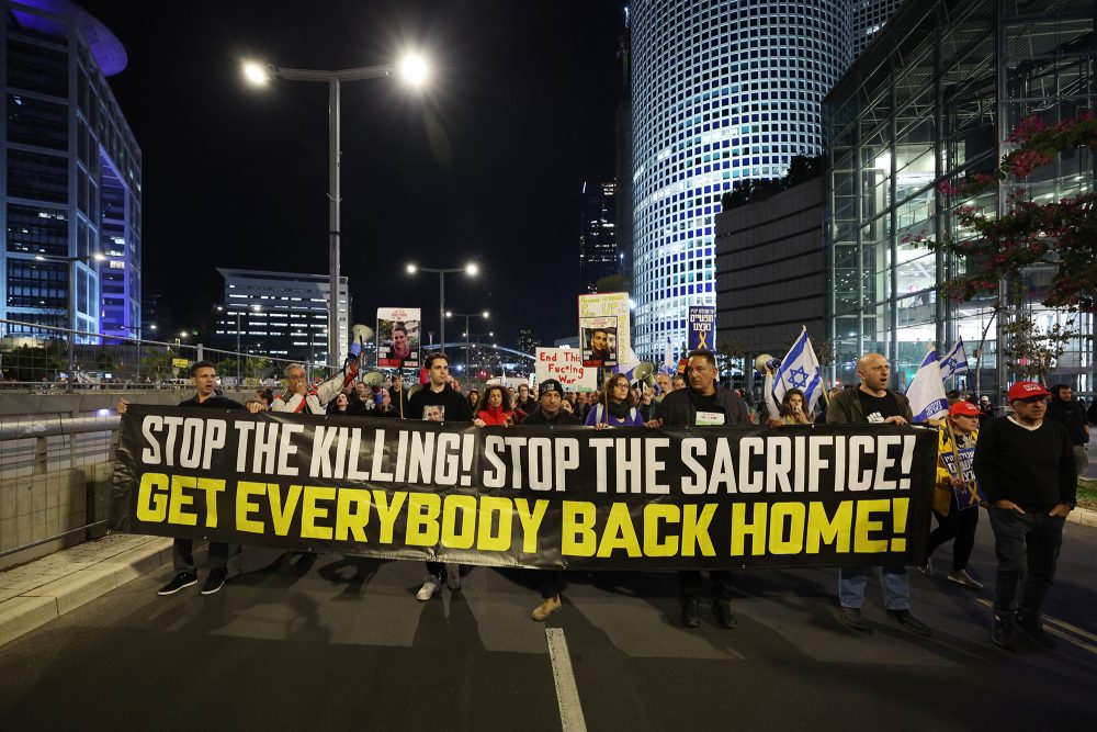 Demonstranten halten bei einer Protestkundgebung vor dem israelischen Verteidigungsministerium in Tel Aviv Schilder hoch und schwenken Fahnen