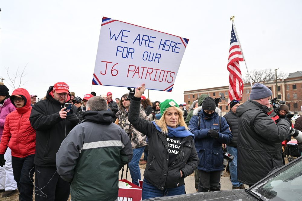 Trump-Anhängerin Sandy Weir, die selbst bis Februar im Gefängnis saß, hält vor der DC Central Detention Facility in Washington, DC, ein Plakat in die Höhe mit der Aufschrift "Wir sind hier für unsere Patrioten des 6. Januar"