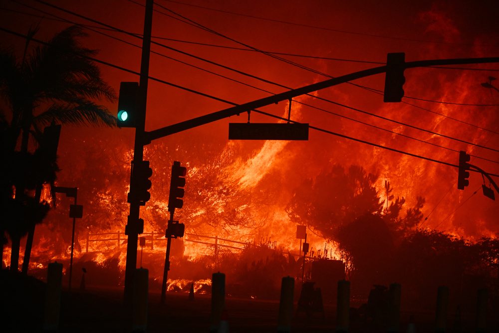 Ein Waldbrand wütet lichterloh in Pacific Palisades in Kalifornien, im Vordergrund ist eine Straßenkreuzung mit Ampeln zu sehen