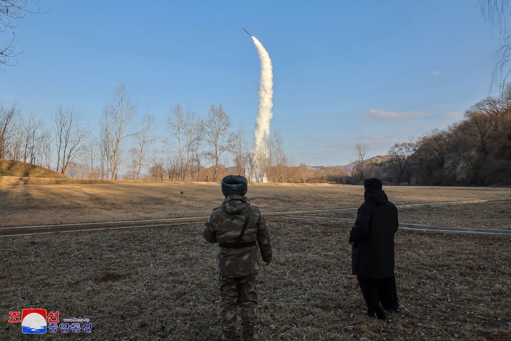 Von hinten sind zwei Männer zu sehen, die zusehen, wie eine Rakete in den Himmel steigt - einer der beiden Männer soll Nordkoreas Staatschef Kim Jong Un sein