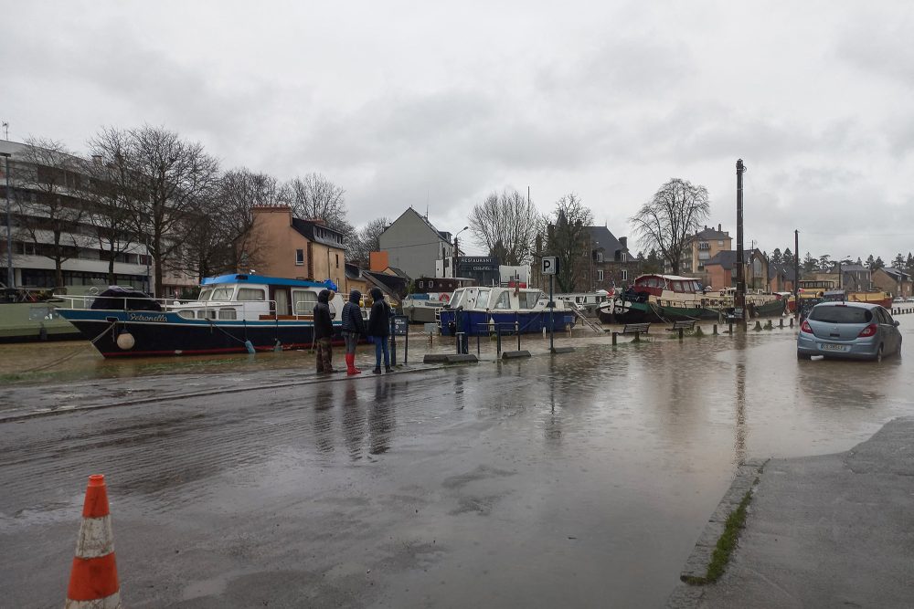 Menschen stehen auf einer teilweise überfluteten Straße nach der Überflutung des Flusses Ille in Rennes