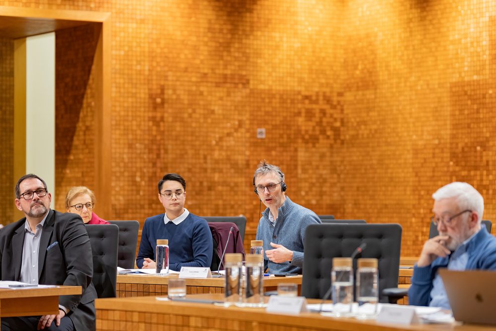 Politiker und Bürger sitzen im Parlament der DG