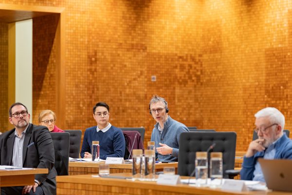 Politiker und Bürger sitzen im Parlament der DG
