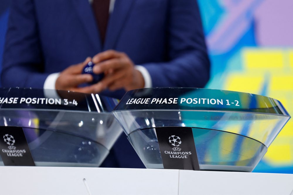 Das Logo der Champions League auf einer der Ziehungsschalen, im Hintergrund sind die Hände eines Mannes zu sehen, der die Ziehung vornimmt