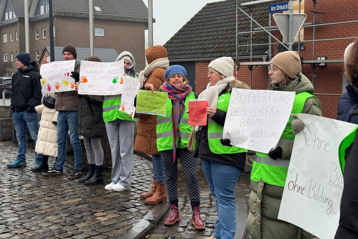 Demonstranten stehen auf dem Dorfplatz in Raeren und halten Poster und Schilder in die Höhe