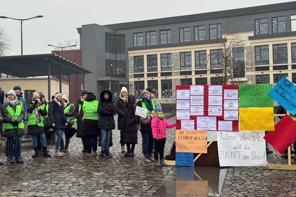 Demonstranten stehen auf dem Dorfplatz in Raeren und halten Poster und Schilder in die Höhe