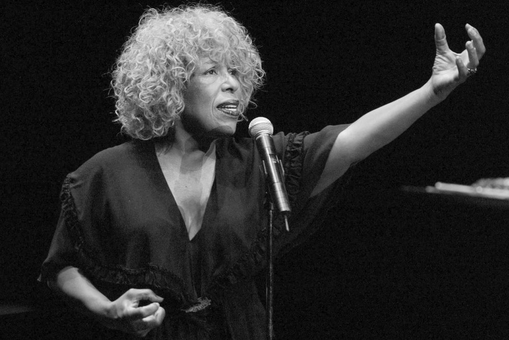 Auf einem Schwarz-Weiß-Foto ist Sängerin Roberta Flack zu sehen mit einem Mikrofon vor sich