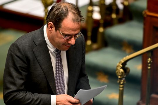 Arbeitsminister David Clarinval steht am Rednerpult und schaut auf Zettel, die er in den Händen hält