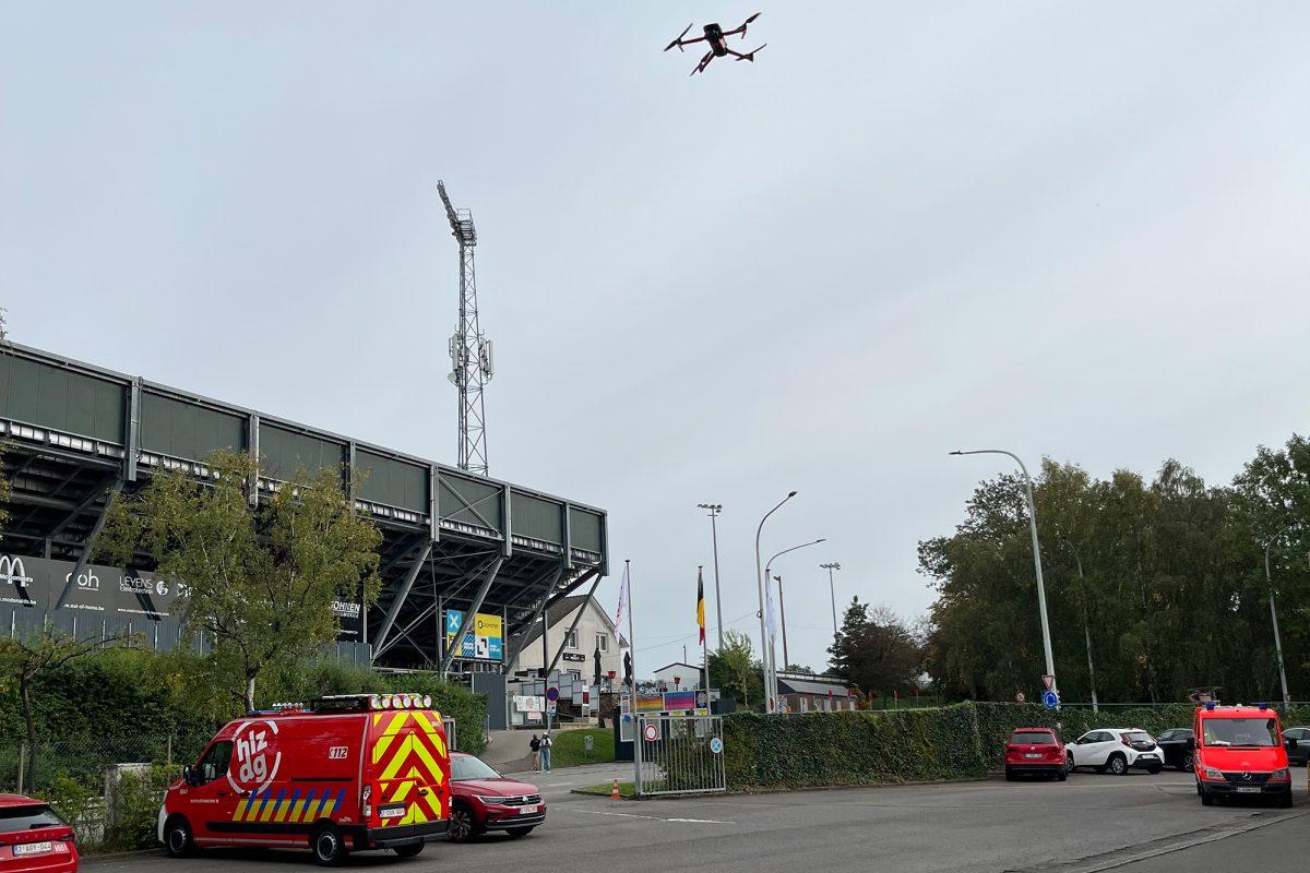 Die Feuerwehr-Aufklärungsdrohne ist geschätzt 20 bis 30 Meter in der Luft über dem Gelände der Eupener Feuerwehr, im Hintergrund ist das Kehrwegstadion zu sehen