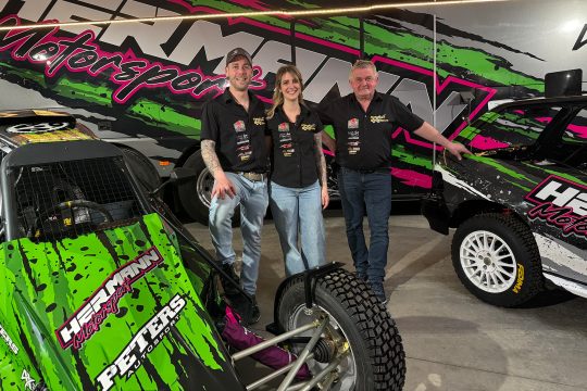 Steven Hermann, Rieke Gillessen und Rainer Hermann posieren für ein Foto neben dem grünen Buggy, mit dem Steven bei Rennen antritt