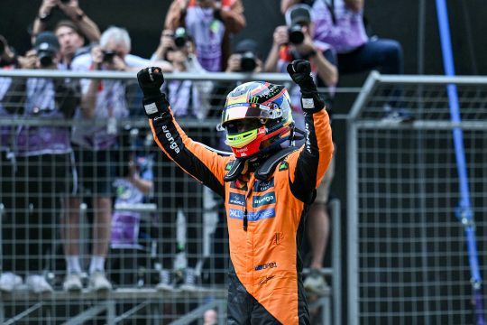 Der australische McLaren-Pilot Oscar Piastri reckt beide Arme in die Höhe und jubelt